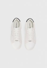Zapatillas blancas y rosa claro con cordones blancos, acento negro en el talón, textura suave y detalles en herrajes plateados en el lado.