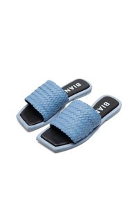 Sandales slides tissées bleu clair avec semelles intérieures rembourrées noires et design à bout carré, présentées sur un fond blanc.