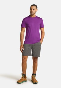 Lilla kortærmet t-shirt, grå shorts og brune vandresko med grønne detaljer, der har en afslappet pasform og letvægtsstof.