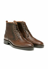 Bottines en cuir marron avec une finition lisse, un bout pointu, un laçage à l'avant et un talon empilé. Les coutures latérales ajoutent une texture.