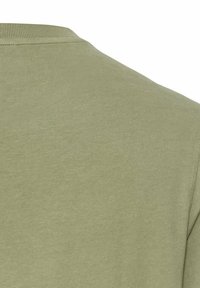 Olivengrøn bomuld T-shirt med rund halsudskæring og korte ærmer. Glat tekstur, ingen mønstre eller hardware-detaljer synlige.