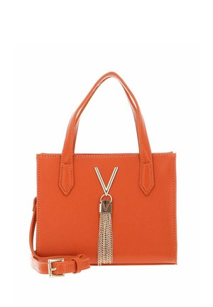 Sac à main en cuir orange avec deux poignées, bandoulière détachable et décoration en chaîne à pompons dorée en forme de V sur le devant.