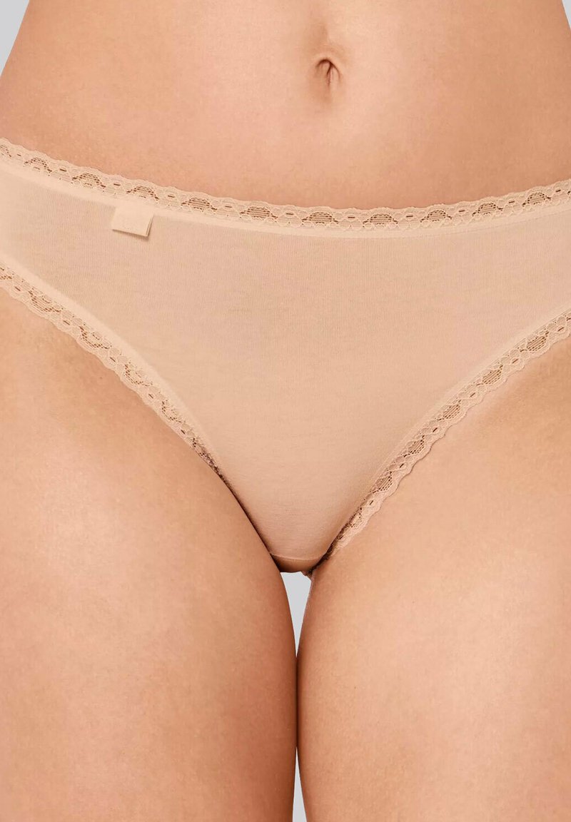 Beige Unterwäsche mit Spitzenbesatz aus weichem Material. Sie hat ein niedrig sitzendes Design und eine glatte Textur mit einer zarten Wellenkante entlang des Bundes.