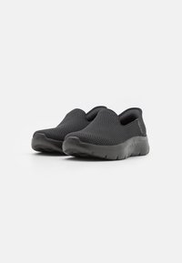 Scarpe slip-on nere in rete con punta arrotondata e suola in gomma spessa, caratterizzate da un design testurizzato e aperture elastiche per una facile indossabilità.