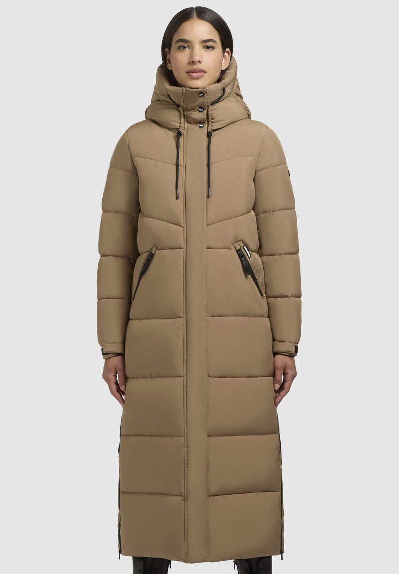 Lange, puffy bruine jas met een capuchon, voorzien van ritszakken aan de zijkanten, zwarte hardware accenten en een horizontaal gestikt patroon.
