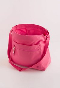Pink, soft fabric shoulder bag with an adjustable strap, exterior zip pocket, and smooth texture; spacious interior with a small inner pocket.
