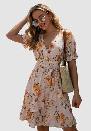 Vestido floral con mangas cortas con volantes, escote en V profundo y cintura ajustada con un cinturón. Presenta una base rosa claro con patrones florales en naranja y verde.