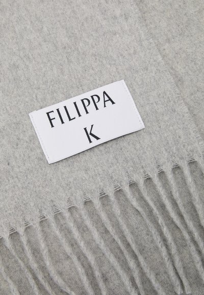 Fringed szürke gyapjú sál fehér címkével, rajta fekete betűkkel "FILIPPA K" felirattal, amely a puha textúrát és az egyszerű dizájnt hangsúlyozza.