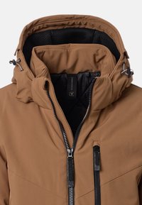 Giacca isolante marrone con collo alto, cappuccio regolabile, fodera in rete nera e tasche con zip a contrasto. Texture esterna liscia e sleek.