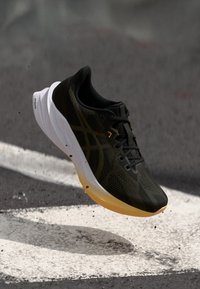 Chaussure de course noire avec une tige texturée, un design élégant, une semelle jaune et des détails accentués. Légère et dotée d'une construction en maille respirante.