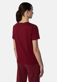 Camiseta de algodón burdeos con mangas cortas, cuello redondo y corte relajado. Textura suave con un diseño minimalista y sin características prominentes.