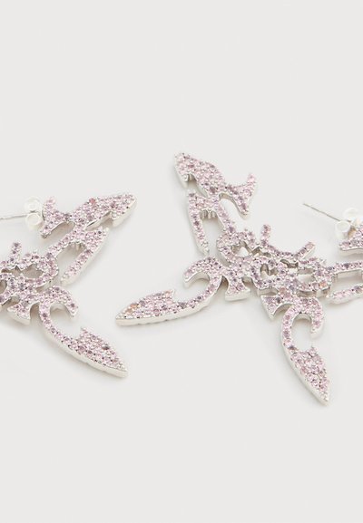 Ασημένια σκουλαρίκια με περίτεχνα λουλουδάτα σχέδια, διακοσμημένα με ροζ κρυσταλλάκια, δημιουργώντας μια υφή επιφάνεια.