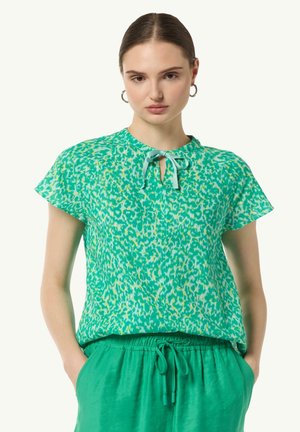 Green short-sleeve top with a leopard print pattern, featuring a keyhole neckline tied with a ribbon. Lightweight, smooth fabric.