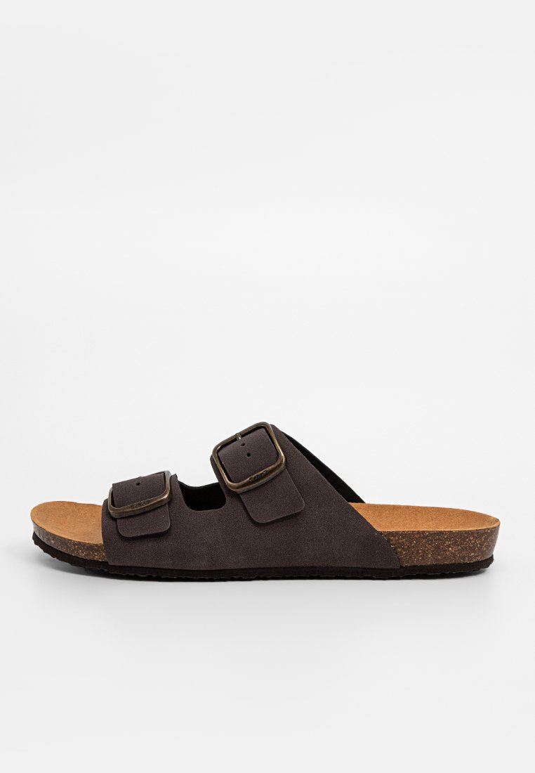 Sandales en daim brun avec deux brides réglables, semelle en liège et semelle extérieure en caoutchouc texturé. Présente des accents en métal de boucle.