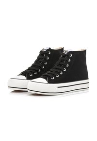 Sneaker alte nere con punta e suola in gomma bianca. Presentano lacci neri e una tomaia in tessuto testurizzato, accentuata da strisce bianche.