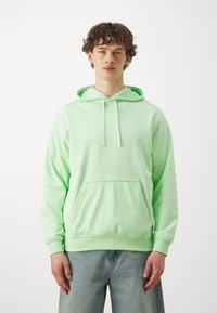 Sweatshirt verde-claro com capuz, bolso frontal e cordão. Apresenta um pequeno logótipo branco no peito. Feito de tecido suave.