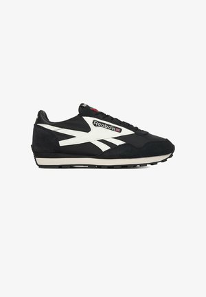 Zapatilla Reebok en blanco y negro con detalles de ante, diseño con cordones y logotipo con la bandera del Reino Unido en el lateral.