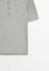 Chemise en tricot côtelé gris clair à manches courtes avec une patte de boutonnage comportant trois boutons sur le devant.
