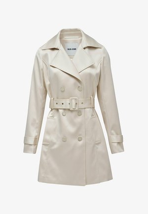 Abrigo trench beige de doble botonadura hecho de tela suave, con cintura ceñida, grandes solapas y dos bolsillos delanteros con detalles de botones.