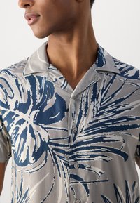 Cămașă cu mânecă scurtă, cu un model floral gri și bleumarin. Fabricată dintr-un material neted; cu guler și nasturi pe partea din față.