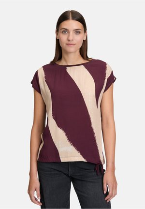 Haut à manches courtes présentant un motif abstrait bordeaux et beige, fabriqué dans un tissu léger avec un col rond et un détail de nœud latéral ajustable.