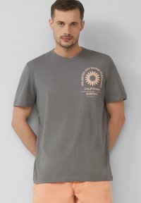 Szary bawełniany t-shirt z grafiką brzoskwiniową przedstawiającą słonecznik i napis. Krótkie rękawy i okrągły dekolt, luźny krój.
