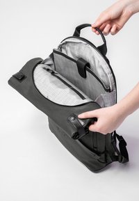 Schwarzer Rucksack aus glattem Material, mit einem gemusterten Futter, mehreren Fächern und einem kleinen oberen Griff.