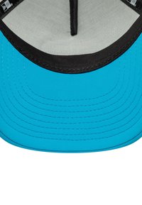 Casquette bleue avec une visière noire, en tissu lisse et présentant des lignes de couture visibles le long des bords. L'intérieur montre un doublage en tissu clair.