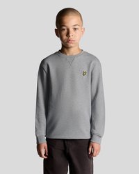 Sweatshirt gris à manches longues avec un col rond et des poignets côtelés, arborant un petit logo jaune sur la zone gauche de la poitrine.