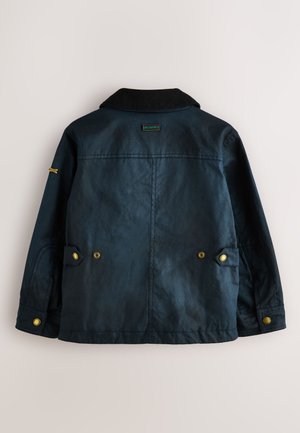 Dunkelblauer, strukturierter Mantel mit schwarzem Strickkragen, zwei großen Fronttaschen und Messing-Druckknöpfen. Rückseite mit eingesticktem Logo.