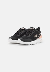 Schwarze Sportschuhe mit Obermaterial aus Mesh, weißer Sohle und roségoldenen Akzenten. Rundliche Zehenform mit Schnürung vorne und gepolstertem Absatz.