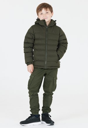 Grön puffjacka med huva, dragkedjestängning och ribbade ärmslut. Matchat med gröna cargobyxor med sidofickor. Svarta sneakers.