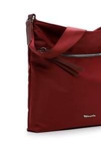 Red nylon shoulder bag with a zippered pocket, flat design, adjustable strap, and a small logo detail near the base.