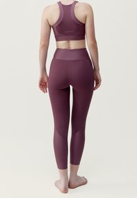 Bordó sportovní podprsenka a legíny, vyrobené z hladkého, elastického materiálu. Design zahrnuje zadní výstřih a vysoký pas s švy.