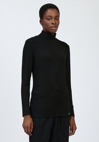 Schwarzes Turtleneck-Oberteil mit langen Ärmeln, aus glattem Stoff gefertigt, figurbetontes Design, mit hohem Kragen und einem dezenten Logo-Akzent am Saum.