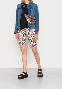 Jeansjacka över en svart topp, i kombination med cykelshorts med leopardtryck och svarta sandaler. Har en midjeväska i leopardtryck.