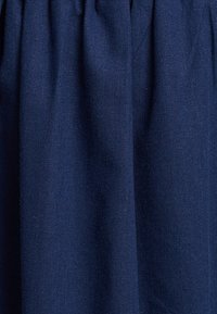 Tkanina w kolorze granatowym o teksturowanym wykończeniu, z marszczonymi fałdami i gładką powierzchnią. Nadaje się do zastosowań w odzieży lub dekoracji wnętrz.