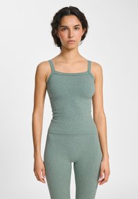 Jasnozielony prążkowany top na szerokich ramiączkach z kwadratowym dekoltem. Dopasowany krój podkreśla sylwetkę, wykonany z miękkiego, elastycznego materiału.