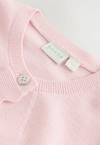 Vaaleanpunainen neulottu neuletakki, jossa on resorireunainen kaulus, yksittäinen nappikiinnitys ja kudottu "BAKER"-tekstillä varustettu etiketti. Pehmeä rakenne ja vaalea sävy.