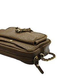 Pochette en cuir texturé marron avec rabat avant, bouton en métal, fermeture éclair et détail de poignée tressée sur fond blanc.