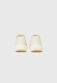 Light beige sneakers with a smooth textured upper, subtle grey accents, a cushioned heel, and a soft rubber outsole.