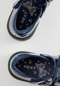 Navy blue patent leather shoes with black soles, featuring adjustable straps and a fabric insole with a butterfly and star pattern. Size 12.