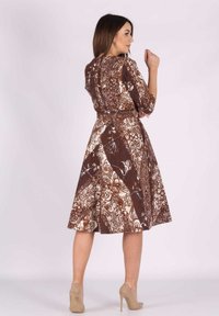 Braunes, gemustertes Kleid mit Dreiviertelärmeln, ausgestelltem Rock und tailliertem Schnitt. Verziert mit kunstvollen Blumen- und geometrischen Designs.