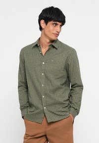 Groene geruite button-up blouse van textuurstof. Heeft een spread collar, lange mouwen en een klein geborduurd logo op de borst.