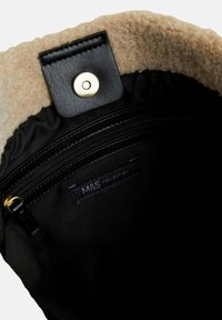 Sort stofpose indre med beige fleeceforing, en guld trykknap og en lynlåslomme med et "M&S Collection"-mærke.