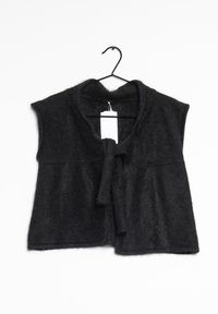 Svart, ärmlös väst gjord av mjukt, texturerat material. Har en knytning i fram och en hängande etikett fästad.