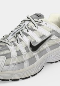 Λευκό και γκρι sneaker Nike με μαύρο swoosh, πλέγμα πάνω μέρος και χοντρή υφή σόλας, με το κείμενο "III 3.0 AIR MAX SERIES" στα κορδόνια.