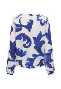 Blouse blanche à manches longues avec de grands motifs floraux abstraits bleus et un tissu texturé, vue de dos sur fond blanc.