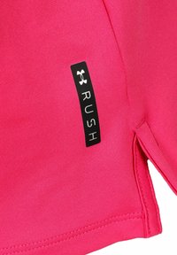 Camiseta deportiva de color rosa brillante con tejido texturizado, aberturas laterales y una etiqueta negra con "RUSH" y el logotipo.