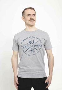 Šedé bavlněné tričko s modrým grafickým designem, na kterém je text "Obránci republiky" a stylizované Jedi symboly.